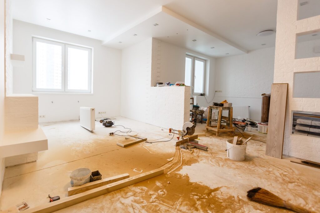 “Home interior under renovation with construction tools, unfinished flooring, and white walls being upgraded by DRR Renovations”